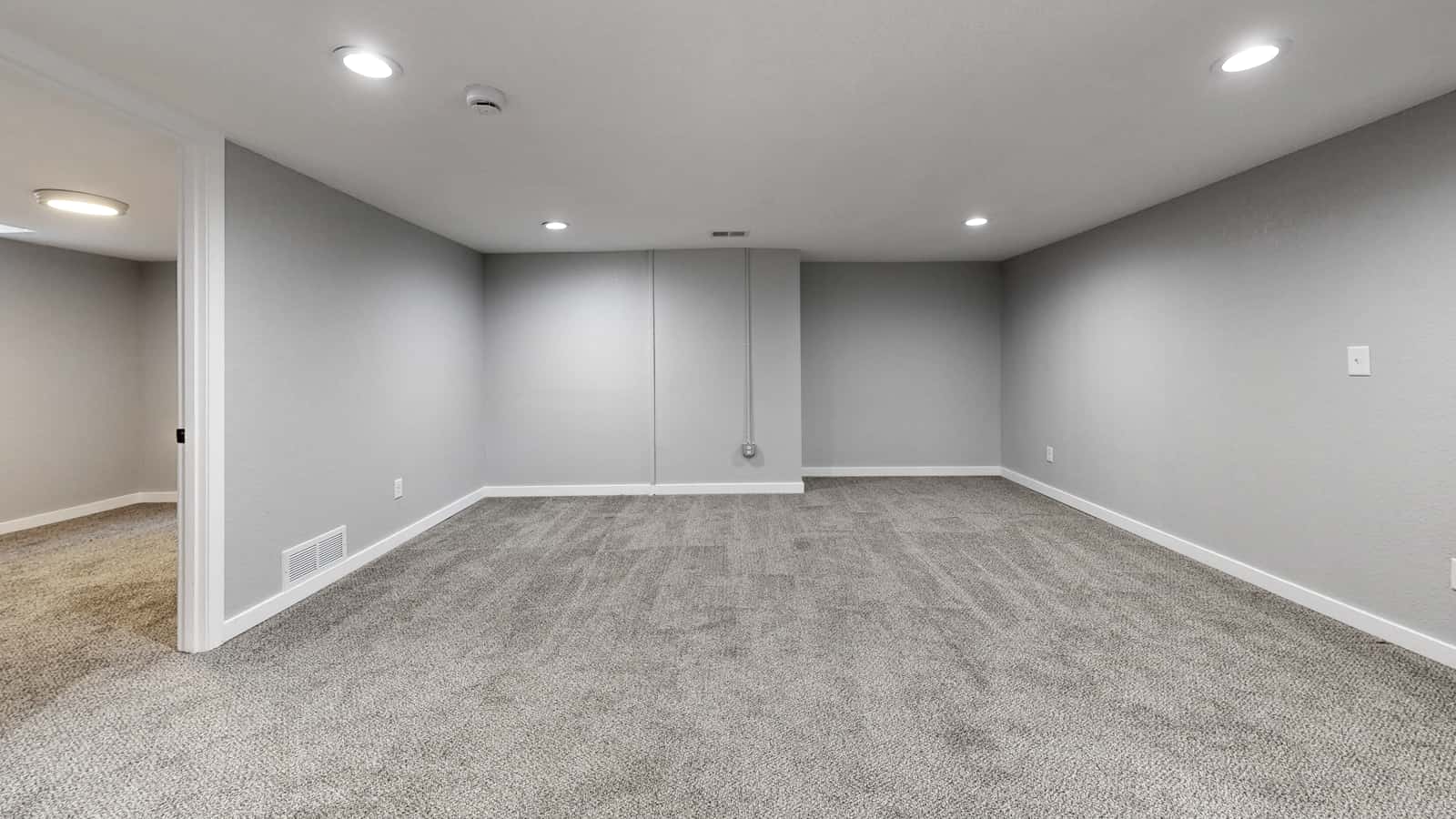 A finished basement room with neutral walls and recessed lighting
