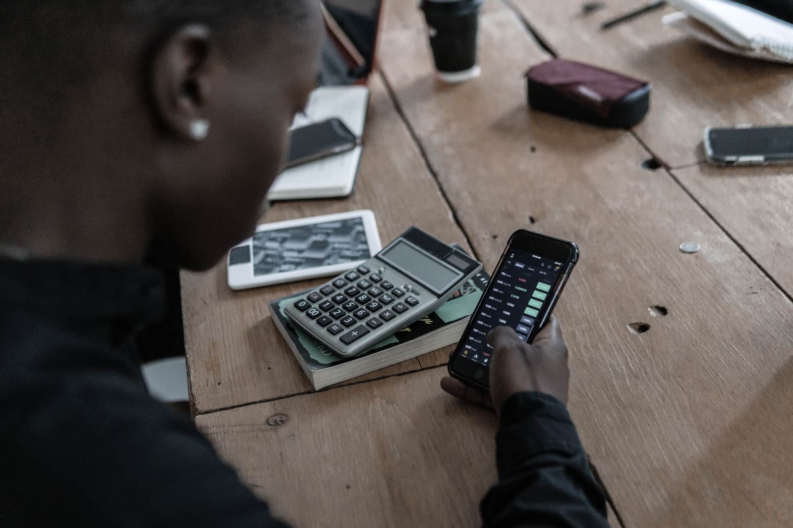 A person working through figures with a calculator at a pale kitchen table