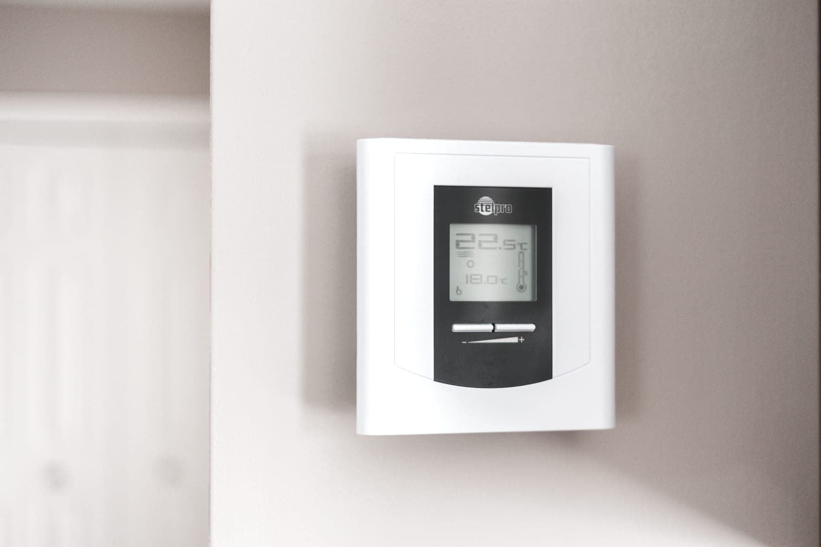 A programmable thermostat mounted on a plain white wall