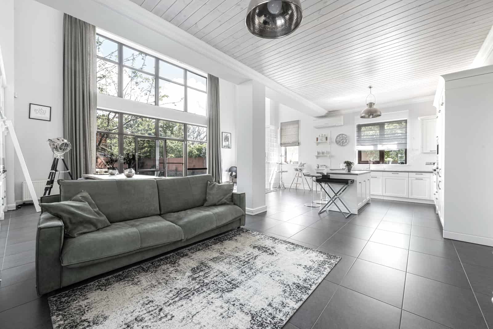 A spacious, brightly lit open-plan living room with a high ceiling