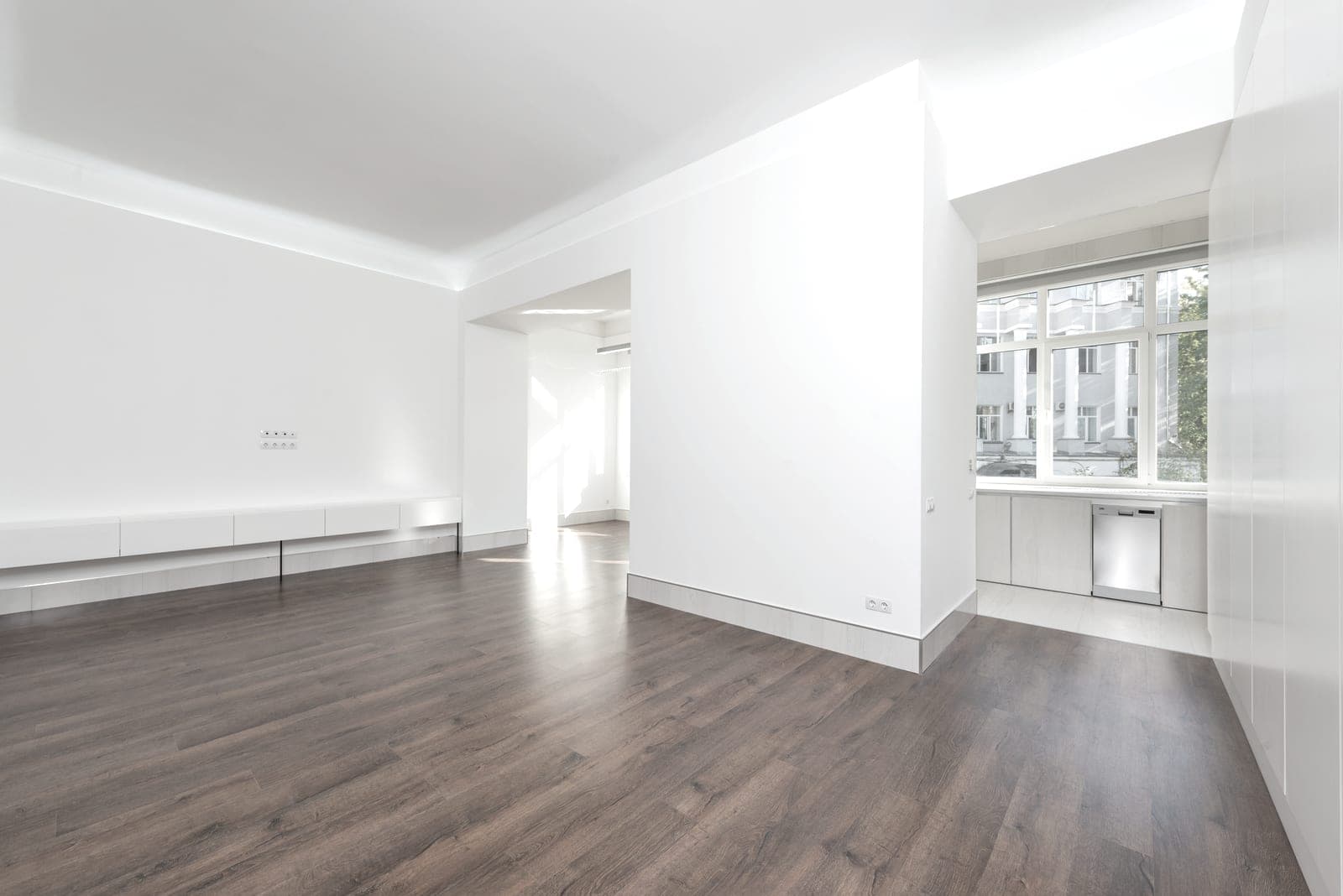 An empty, brightly lit room with pale wooden flooring and white walls