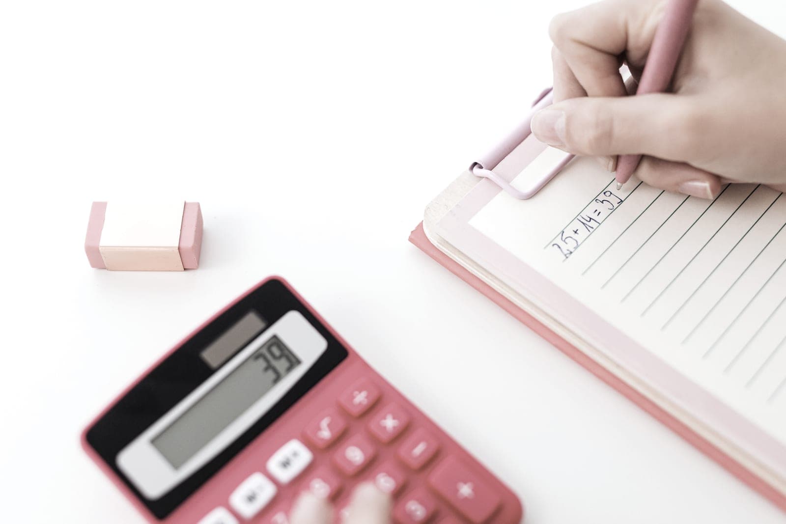 A calculator and a notebook on a pale desk in daylight