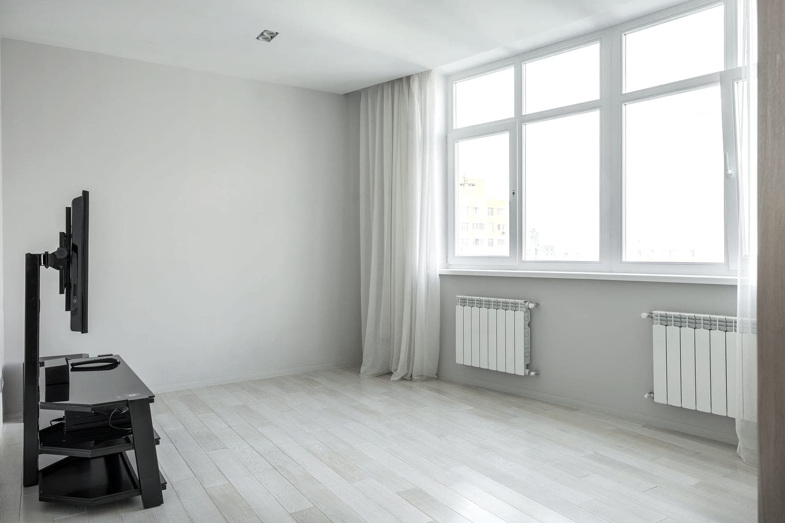 A white panel radiator beneath a window in a bright room